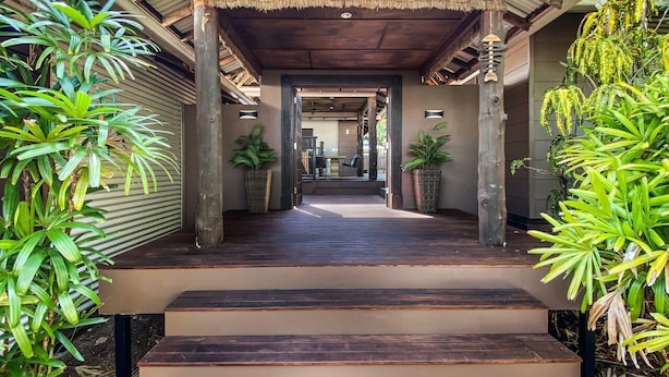 Un passage couvert mène à un bâtiment doté d’un plancher en bois et d’un escalier.