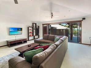 A modern living room with a sofa, coffee table, TV, and a bookshelf.