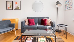 Ett modernt vardagsrum med en grå soffa, ett soffbord i glas och en rund spegel på väggen.