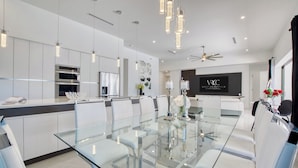 A modern kitchen with stainless steel appliances, a glass dining table, and pendant lighting. - VRCC Villa Sogno - modern-day getaway (Cape Coral)