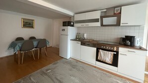 Eine kompakte Küche mit weißen Schränken, einem eingebauten Ofen und einer Essecke mit Tisch und Stühlen.