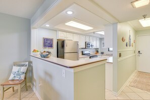 A kitchen with white cabinets, a refrigerator, a microwave, and a sink.