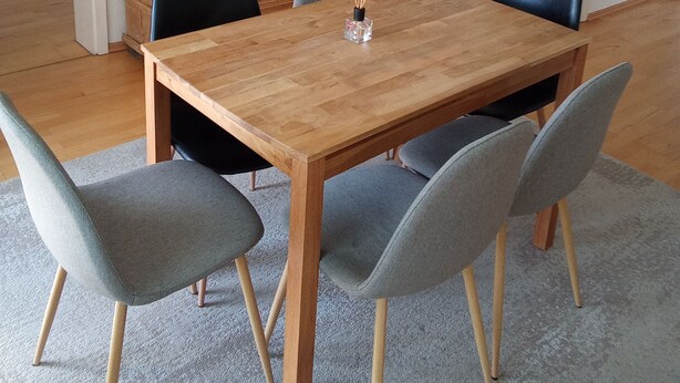 A dining area with a wooden table, four grey chairs, and a cabinet. - Lake Starnberg: Terraces, wood-burning stove  (Münsing)