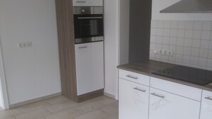 A kitchen with white cabinets, a built-in oven, and a countertop. - Lake Starnberg: Terraces, wood-burning stove  (Münsing)