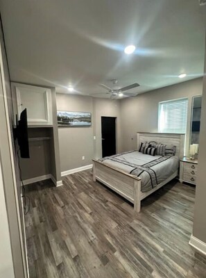 A bedroom with a bed, a ceiling fan, a window with blinds, and a nightstand with a lamp. - Prime OTR+ Queen bed +Parking Unit 6 (Cincinnati)