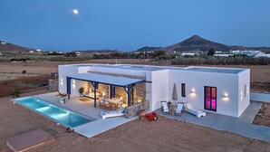 Una villa moderna con piscina, area relax esterna e vista su una montagna.
