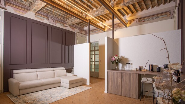 Una sala moderna con sofá, suelo de madera y una zona de cocina con barra.