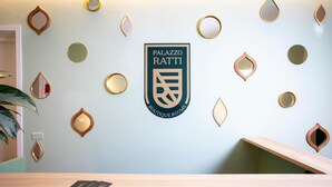 Un mostrador de recepción con el logotipo de Palazzo Ratti Boutique Rooms en la pared.