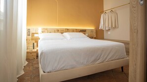 Una cama con ropa de cama blanca en una habitación con suelo de piedra y cabecero de madera.