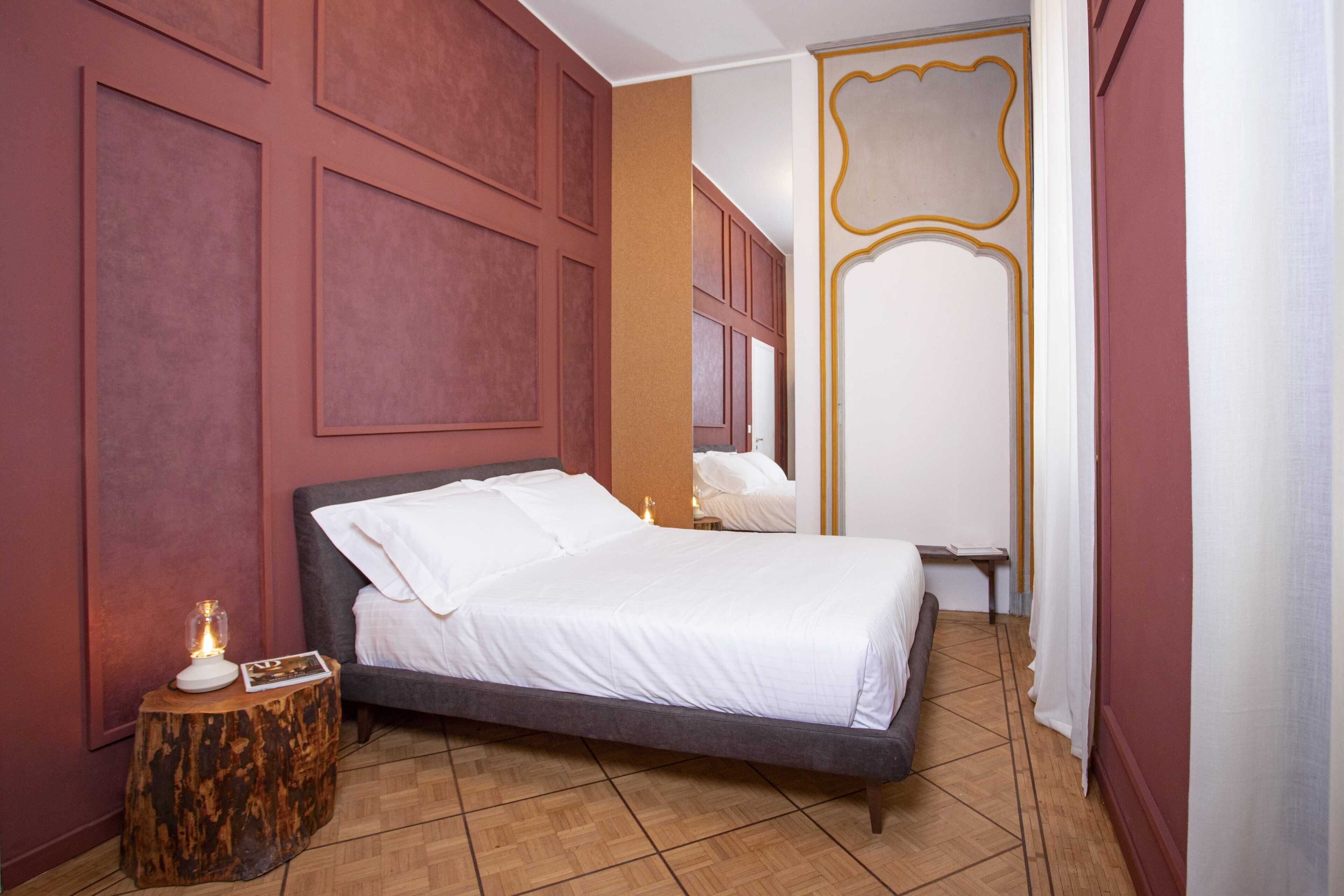 A bedroom with a bed, a nightstand with a lamp, and a wooden side table.