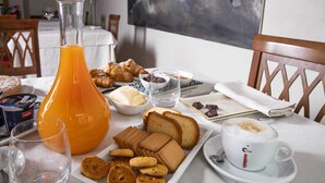 Una mesa de desayuno con cruasanes, pan, pastelería y una taza de café.