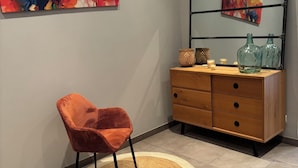 Une pièce comprenant une commode en bois, une chaise, un tapis rond et deux tableaux abstraits accrochés au mur.