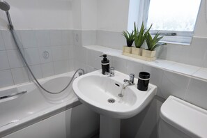 A bathroom with a bathtub, a sink, and a window above the sink. - Beckton Docklands - 1 Bedroom - Sleeps 4 - Wifi (London)