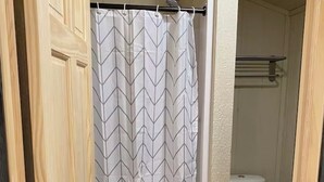 A bathroom with a white toilet, a shower curtain with a chevron pattern, and a wooden door. - O’Neill Ventures’s Queen Cabin with WIFI (Martin)