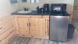 A compact kitchen with a sink, coffee maker, microwave, and a small trash bin. - O’Neill Ventures’s Queen Cabin with WIFI (Martin)