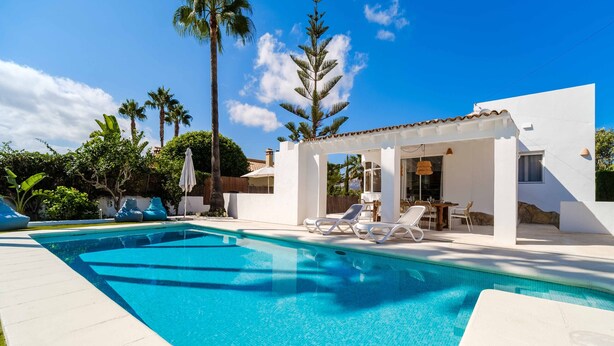 Una piscina con lettini e una zona salotto coperta.