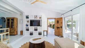 Un soggiorno moderno con televisione, mobili in legno, un divano e un'ampia finestra con vista sull'esterno.