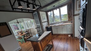 Una cocina con piso de madera, una isla central y una ventana que da a zonas verdes.