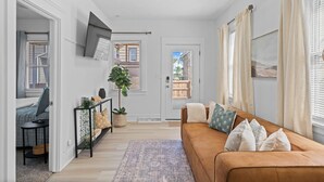 A living room with a brown sofa, a TV mounted on the wall, and a door leading outside. - Comfortable 2- Bedroom House In Cleveland 1330 (Cleveland)