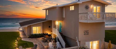 A two-story beachfront property with a balcony, a fire pit, and a view of the ocean.