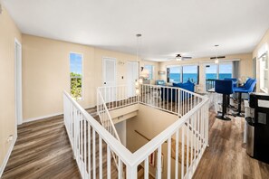 A spacious balcony with a white railing, a dining area with blue chairs, and a view of the ocean. - Melbourne Beach Oceanfront Apartment Unit #2 - Ocean Views (Melbourne Beach)