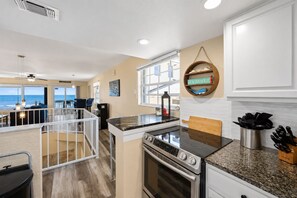 A modern kitchen with a large island, stainless steel appliances, and a view to the ocean. - Melbourne Beach Oceanfront Apartment Unit #2 - Ocean Views (Melbourne Beach)