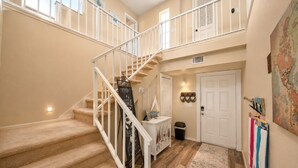 A multi-level interior with carpeted stairs, a white door, a small trash bin, and a wall-mounted map. - Melbourne Beach Oceanfront Apartment Unit #2 - Ocean Views (Melbourne Beach)