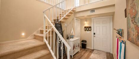 A multi-level interior with carpeted stairs, a white door, a small trash bin, and a wall-mounted map.