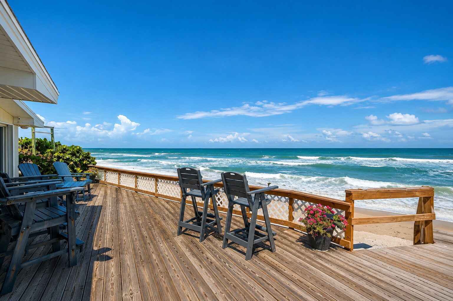 Una terraza de madera con sillas y una mesa con vista al océano.