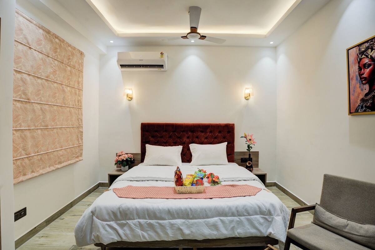 Une chambre d’hôtel bien rangée, avec un grand lit, une tête de lit rouge et une seule chaise.