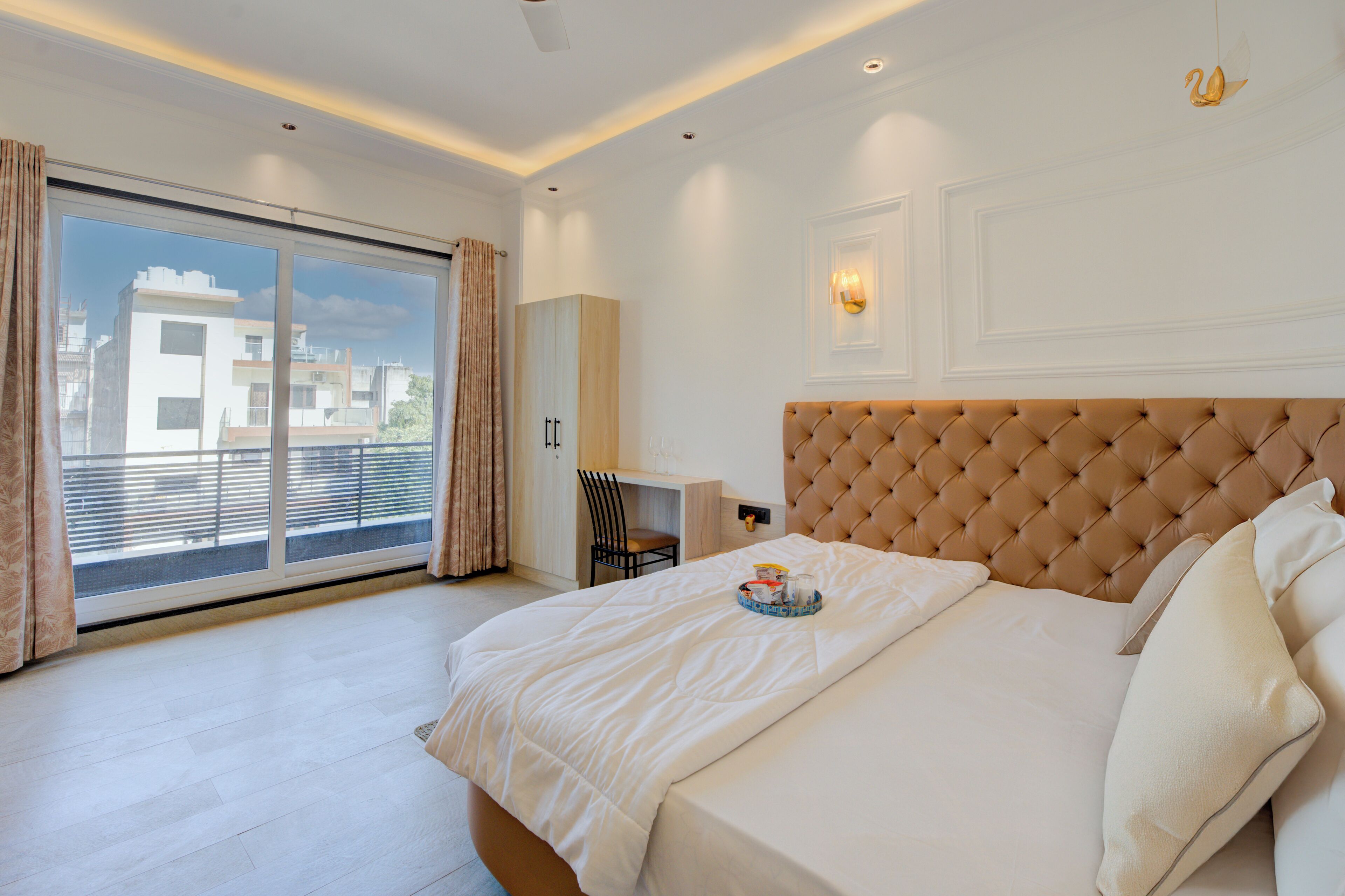 Een slaapkamer met een groot bed, een bureau en uitzicht op gebouwen door een schuifdeur.