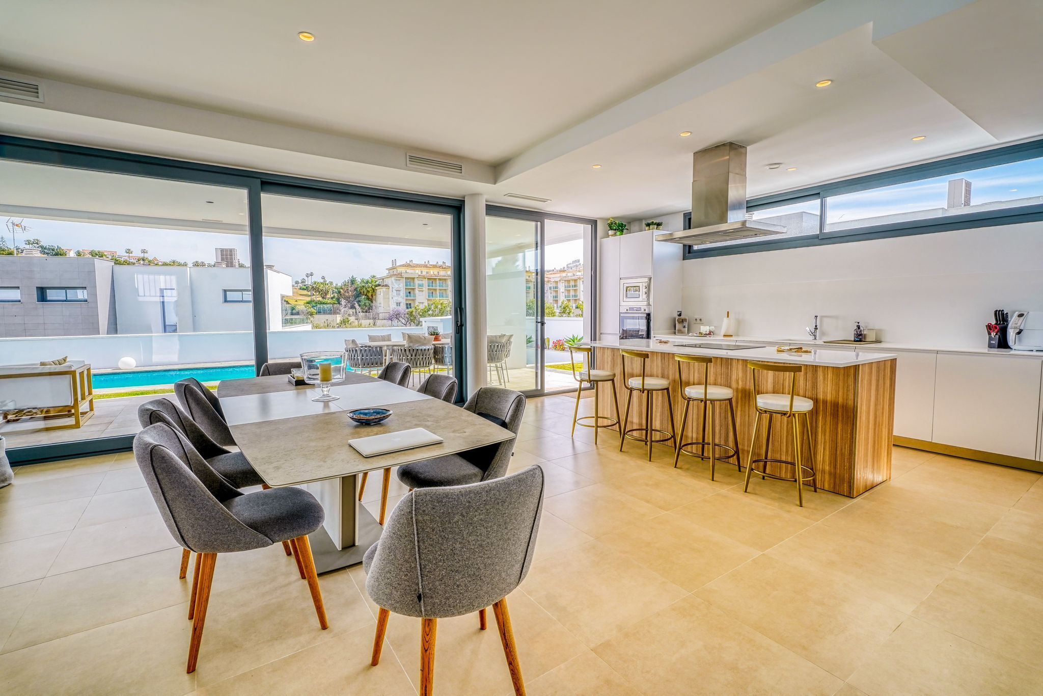 Una cucina moderna con angolo bar, ampie finestre e zona pranzo con sedie.