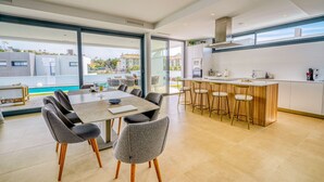 Una cucina moderna con angolo bar, ampie finestre e zona pranzo con sedie.