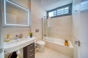 A modern bathroom with a sink, toilet, and glass-enclosed shower. - Beautiful villa with a private pool   (MANILVA)