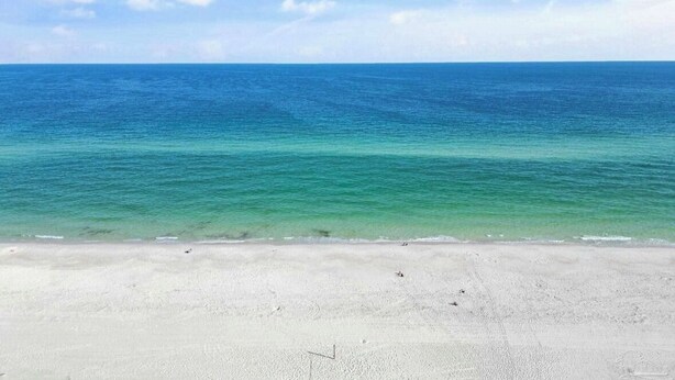 Ein Strand mit klarem türkisblauem Wasser und einem sandigen Ufer.