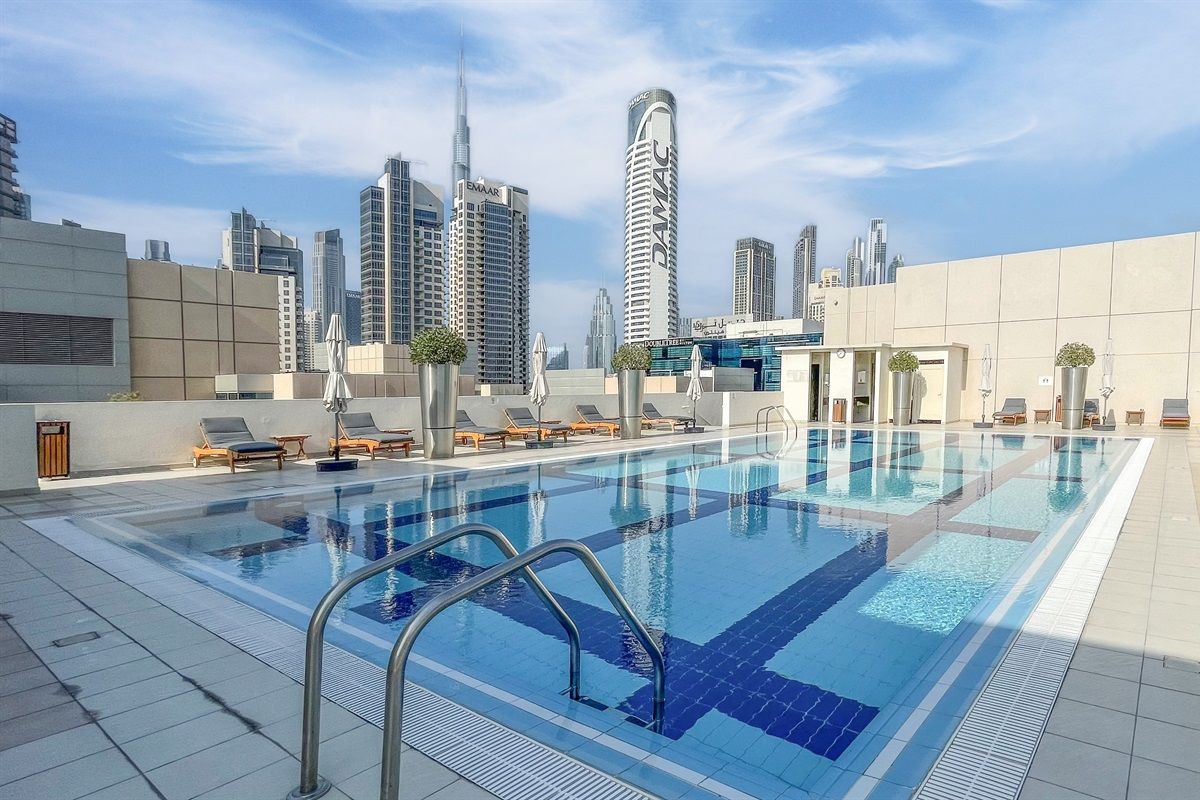 Ein Pool auf dem Dach mit Liegestühlen und einer Stadtansicht im Hintergrund.