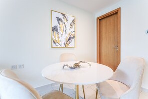 A dining area with a round table, two chairs, a wall-mounted artwork, and a wooden door. - Modern Comfort Studio Near Downtown Dubai (Dubai)