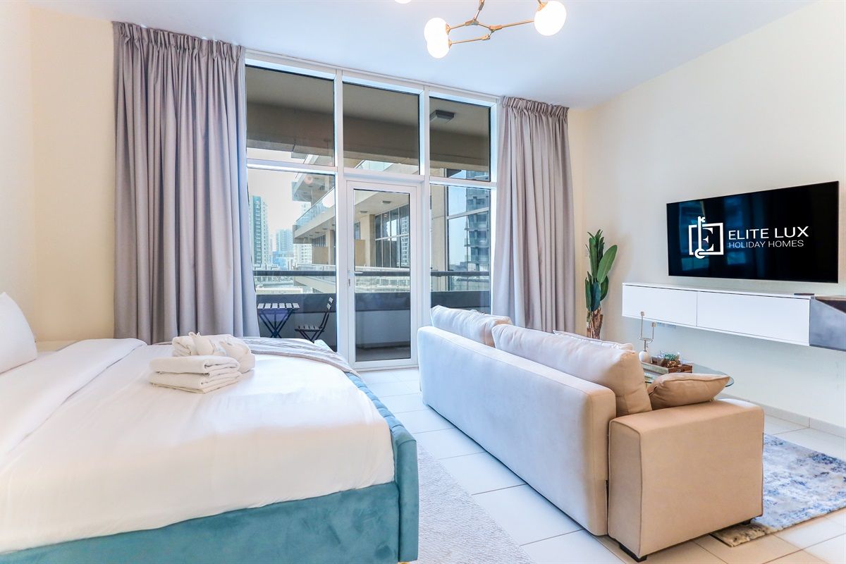 Une chambre d’hôtel moderne équipée d’un lit, d’un canapé, d’une télévision et d’un balcon offrant une vue sur la ville.
