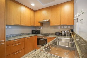 A modern kitchen with wooden cabinets, a microwave, an oven, and a stainless steel sink. - Modern Comfort Studio Near Downtown Dubai (Dubai)