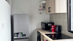 Ett kompakt kök med en inbyggd tvättmaskin, en mikrovågsugn och en diskho i rostfritt stål.