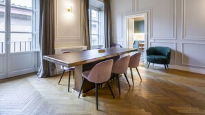 A dining area with a wooden table, six chairs, and a green armchair.
