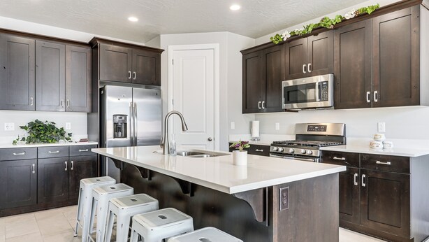 A modern kitchen with dark wooden cabinets, stainless steel appliances, a large island with stools, and a white countertop. - 28 Mi to Zion Nat’l Park: Modern Washington Home (Washington)