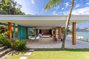 Un espacio exterior moderno con terraza de madera, zona de estar y vista al agua.