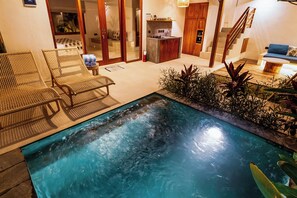 Un espace piscine avec des chaises longues, une cuisine et un escalier.