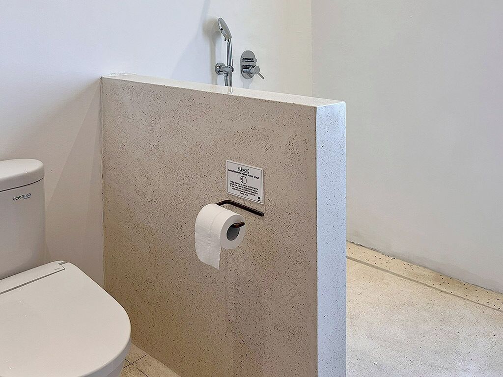 Ein Badezimmer mit Toilette, Dusche und Papierhandtuchspender.