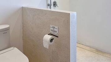 Ein Badezimmer mit Toilette, Dusche und Papierhandtuchspender.