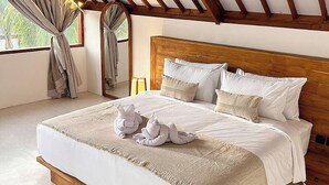 Een groot bed met een houten hoofdeinde, witte beddengoed en twee handdoeken op het bed.