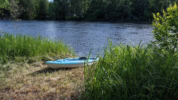 A kayak on the shore of a river with dense vegetation and trees in the background.