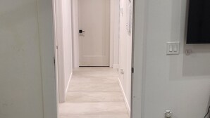 Un pasillo con piso de madera que conduce a una puerta cerrada al final.