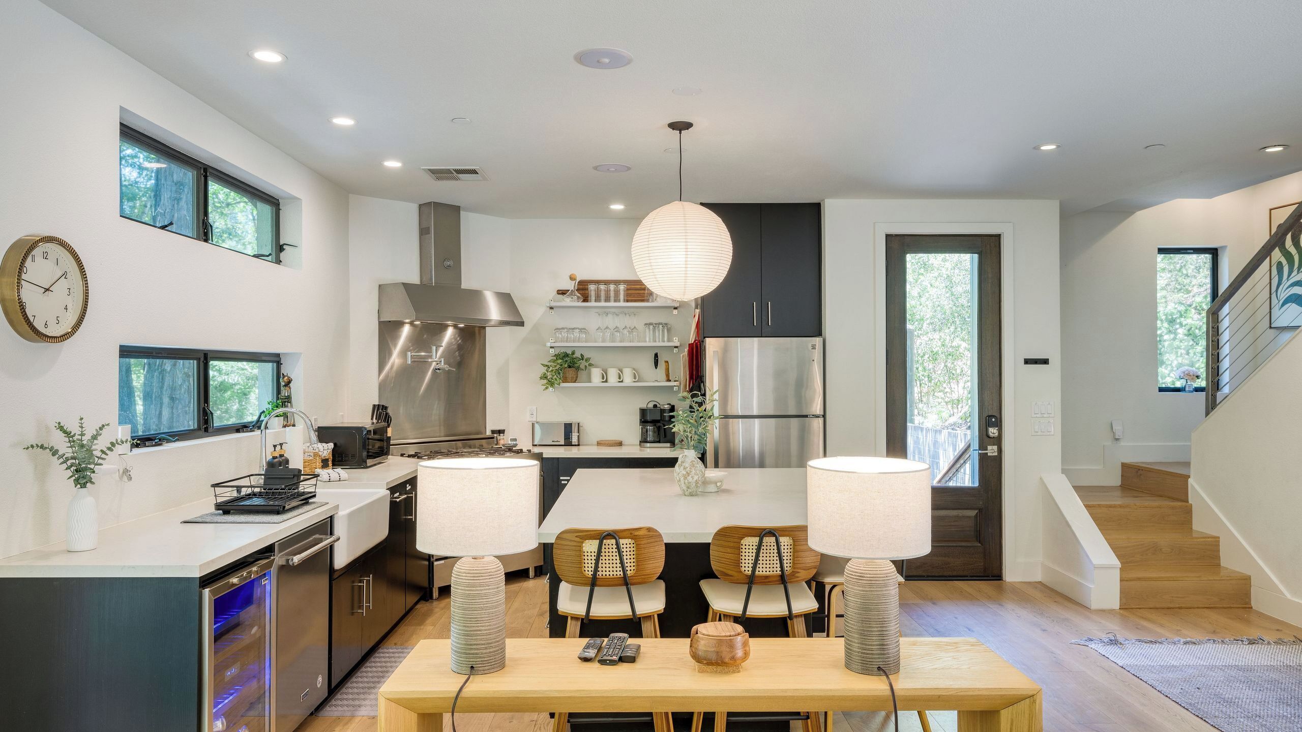 A modern kitchen with a central island, built-in appliances, and a dining area with two chairs and a table.